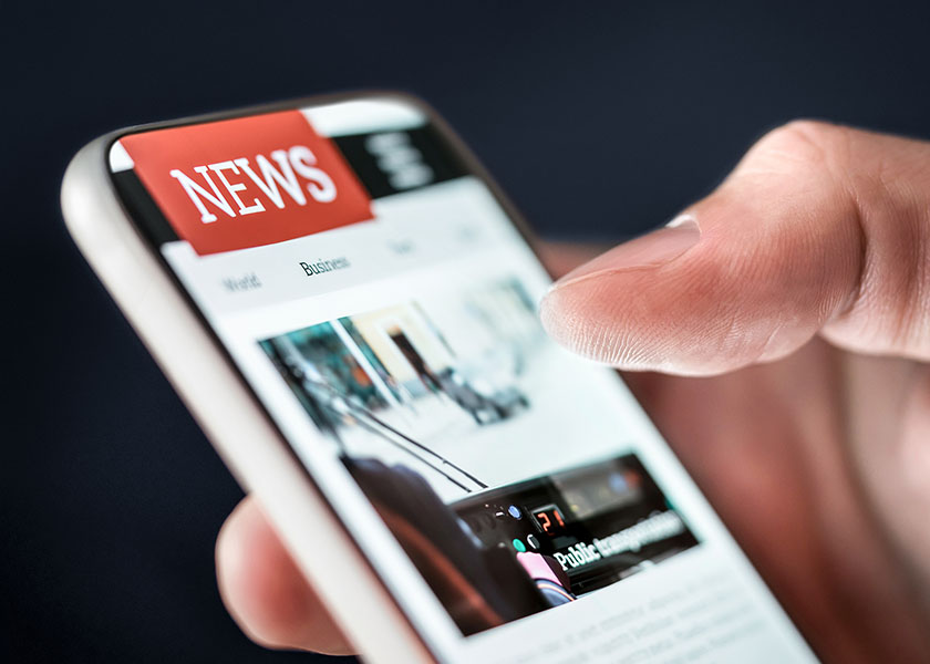 A hand holding a phone with a news page onscreen